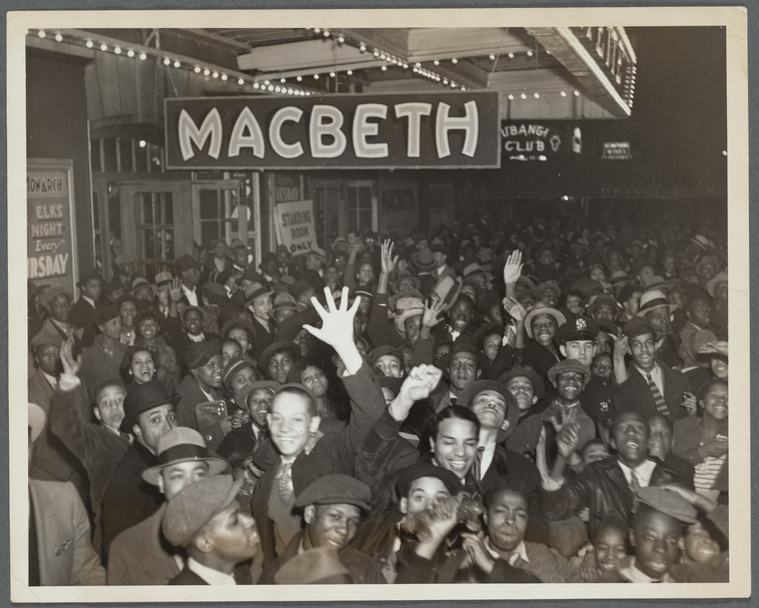 Large crowd under a theater awning with a large sign above them that says Macbeth